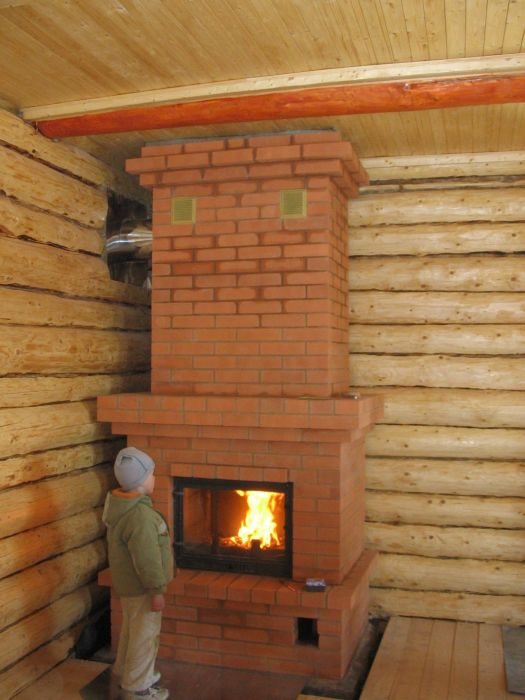 Brick semi-closed fireplace in a wooden house